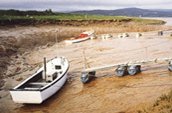 Des bateaux de pêche couchés sur les rives boueuses d’un affluent de la rivière Petitcodiac, attendant la marée.